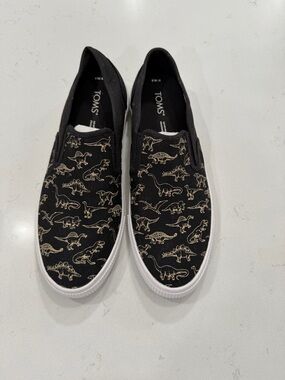TOMS Black Slip-On Sneakers with Gold Dinosaur Outline Print